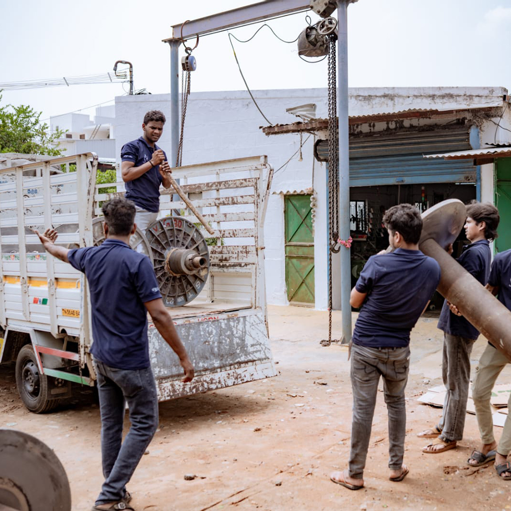 Engineering team manually loading heavy industrial machinery parts onto a transport truck.